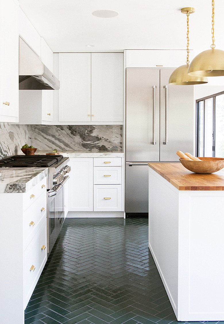 Dark green herringbone kitchen floor with white cabinets and brass pendant lights