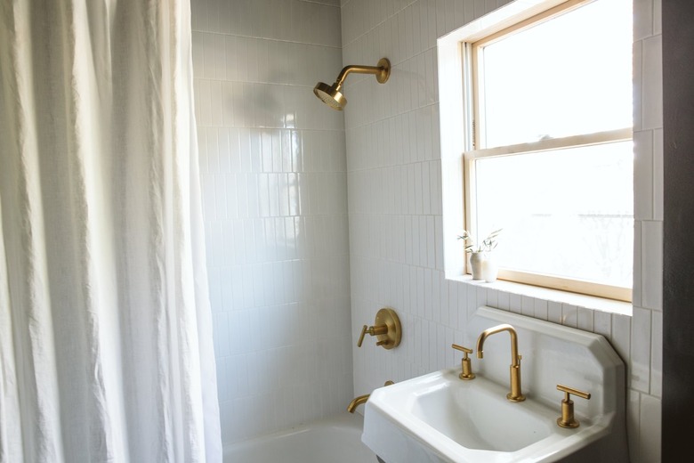 white sink with a gold faucet and white tiles in a bathroom