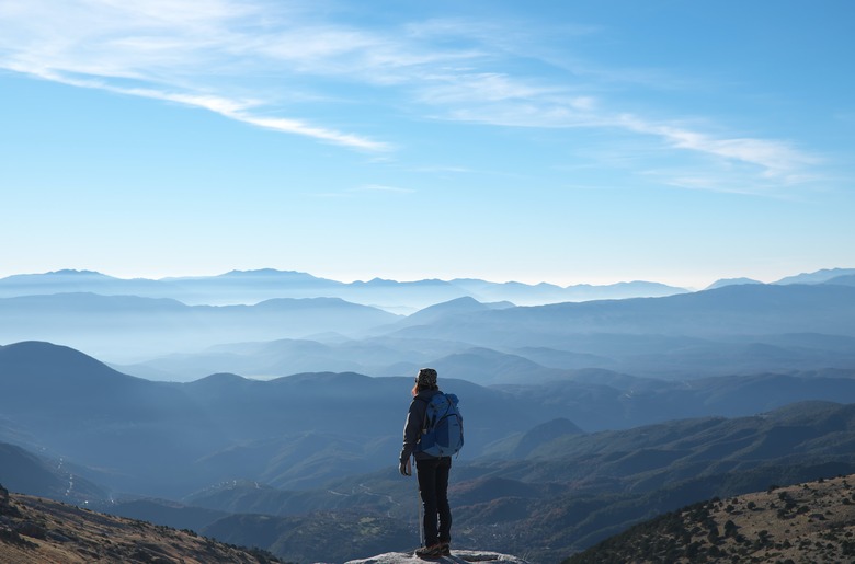 person standing on a tall precipice overlooking a natural view