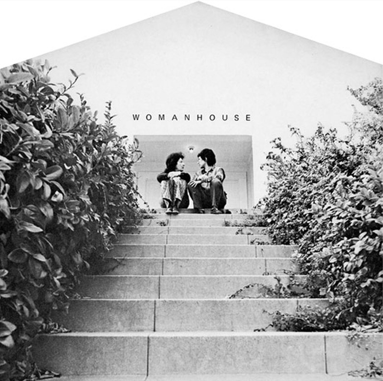 two women sitting on steps near building with the word 