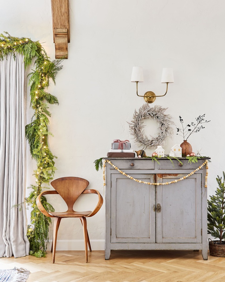 green and gold Christmas colors in living room vignette with cabinet, chair and decorations