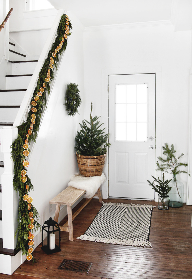 white and green Christmas colors in entryway with garlands and mini tree by the stairs