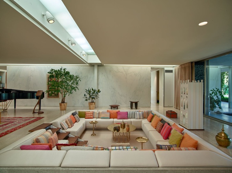 a conversation pit featuring a small wooden staircase in wraparound couch with multicolored pillows