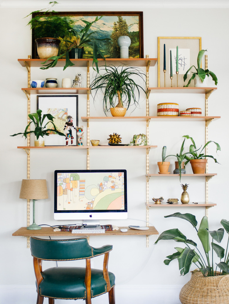 small home office with wall-mounted shelving and green desk chair