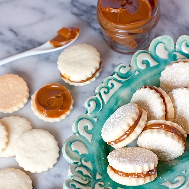 Muy Bueno Cooking Alfajores on blue plate with side of dulce de leche sauce