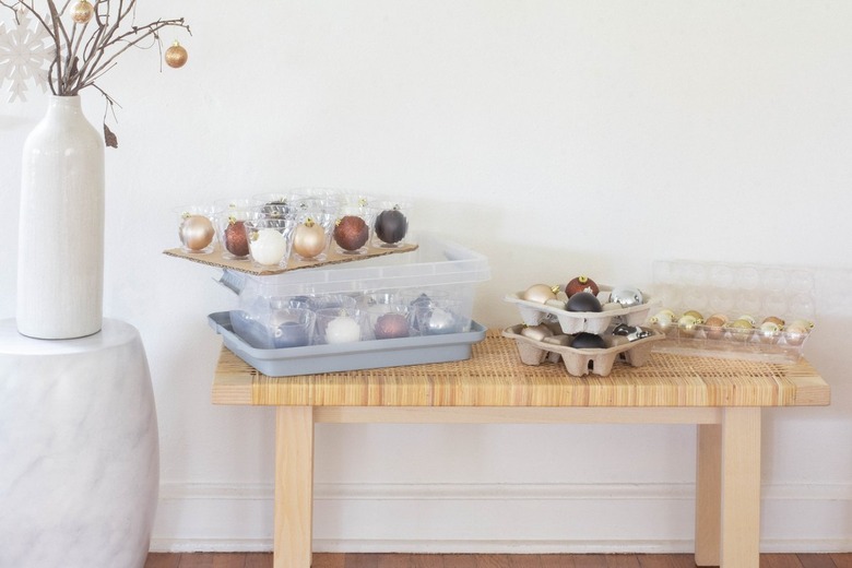 Containers with ornaments next to white vase with dried branches