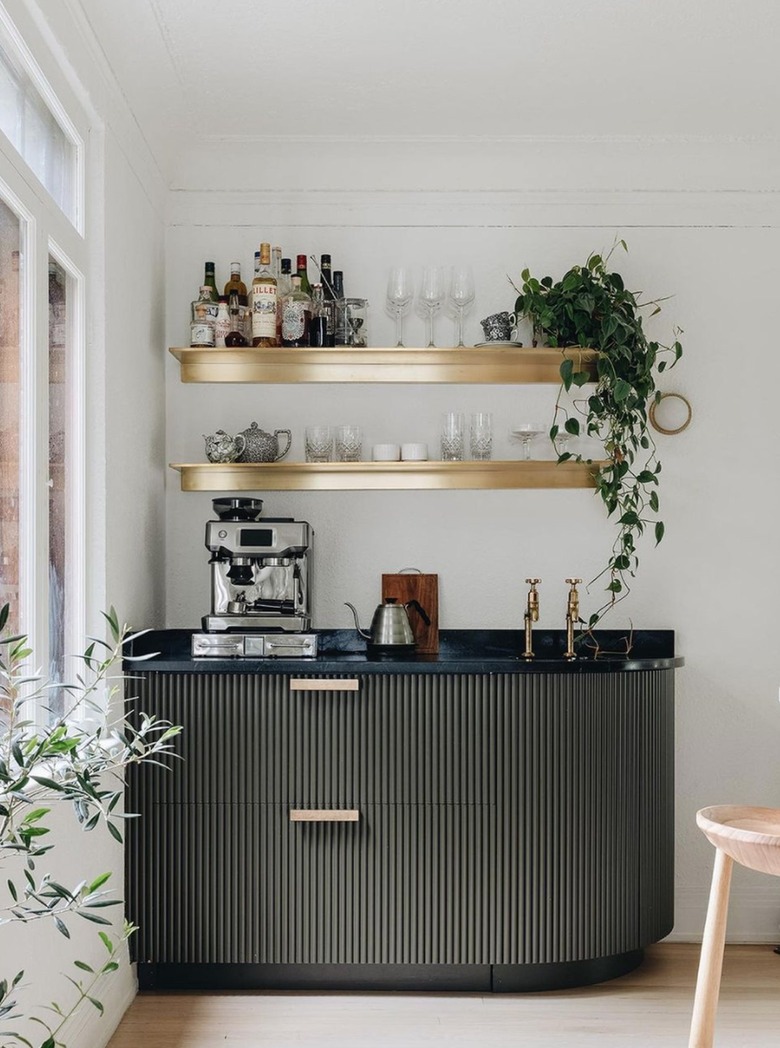 Coffee station and cocktail bar inside a kitchen, shelves, plants, glassware, coffee maker.