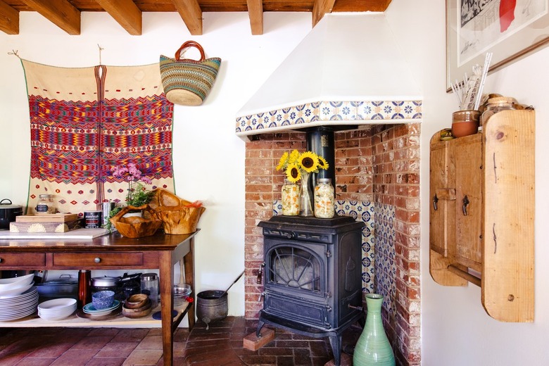 Bohemian kitchen with vintage fireplace in a brick-floral tile alcove, wood furniture, traditional textile, wood beam ceiling