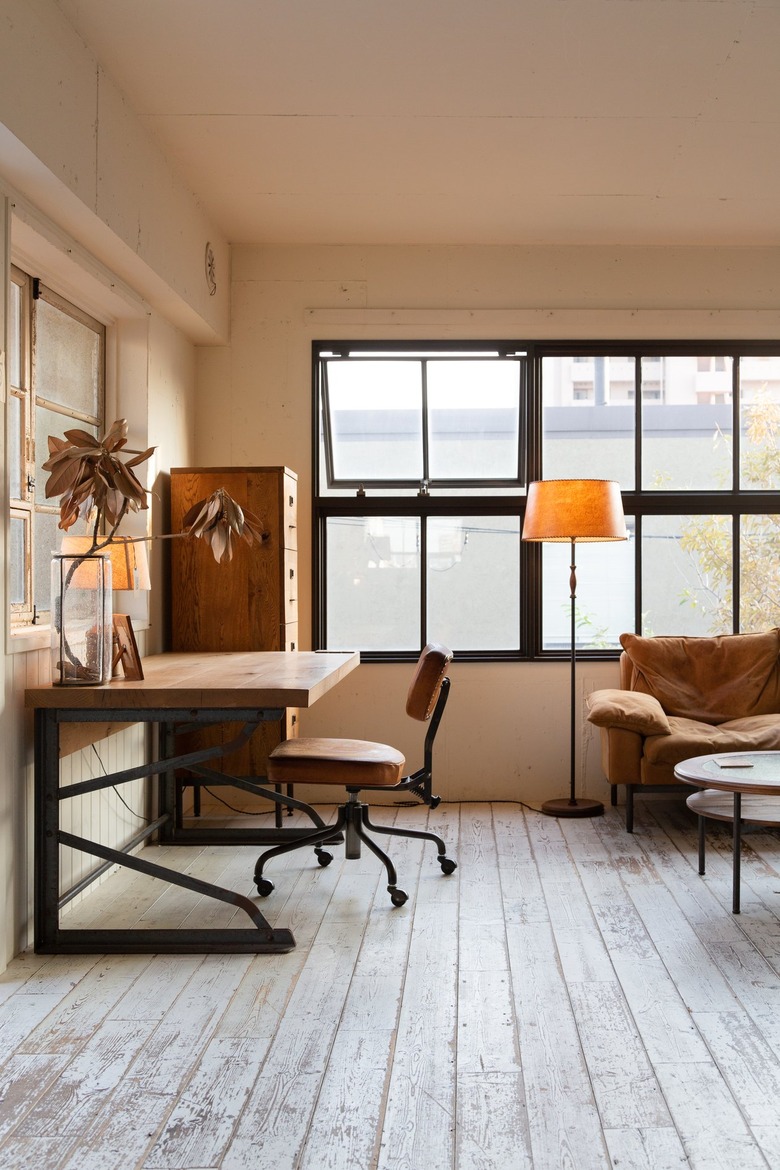 a simple desk made from wooden planks sits next to a wooden filing cabinet and a leather desk chair