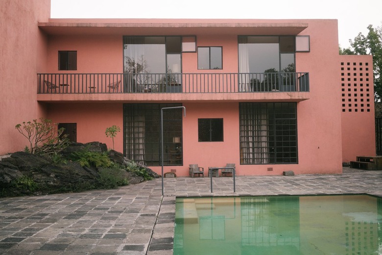 Slate patio with swimming pool and pink Midcentury building with large windows and balcony Home Exterior Ideas