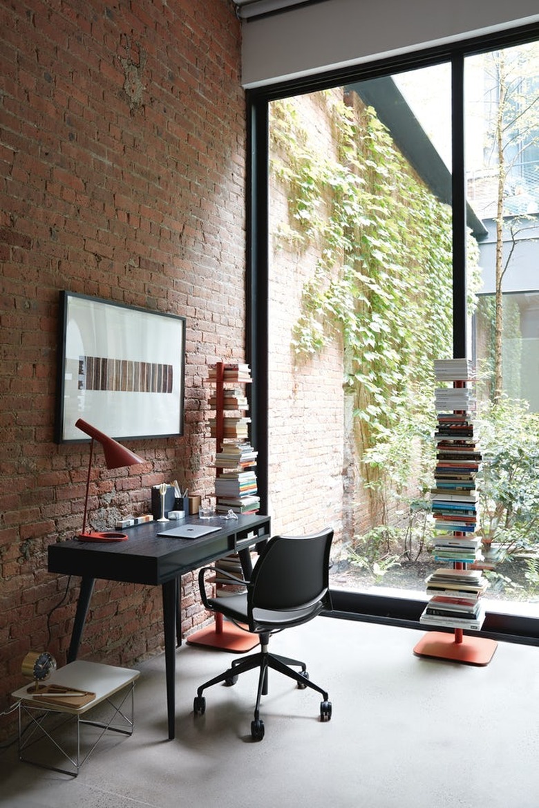 home office with brick wall, balck modern desk, and windows