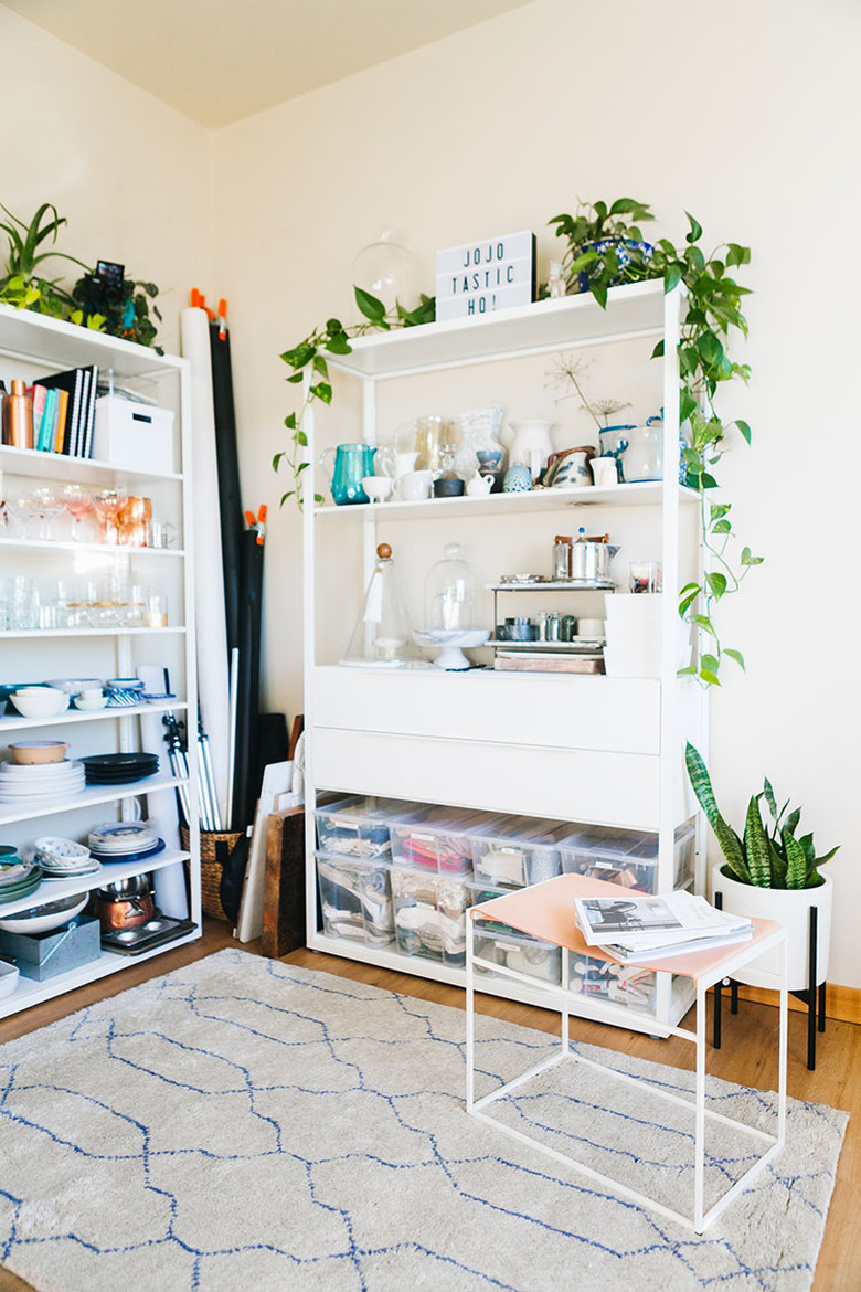 white home office with white open bookshelves with plants on the top shelf