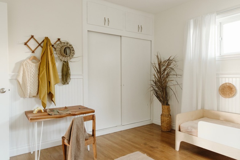 Neutral room with hat rack and plant with toddler bed