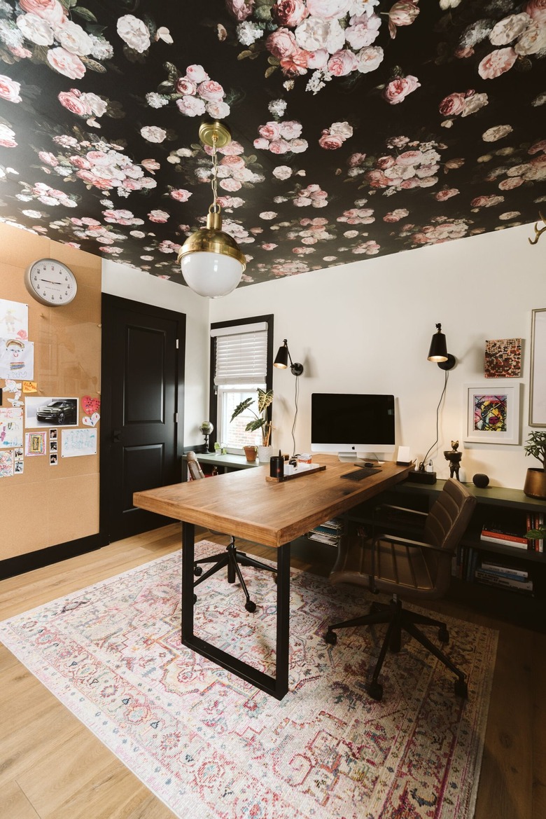 modern home office with wood desk and pendant light hanging from floral ceiling