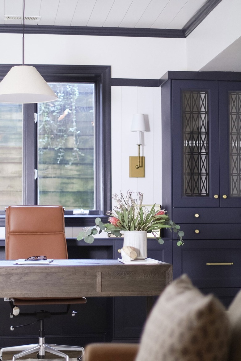 traditional home office with blue built-ins and white fabric pendant light