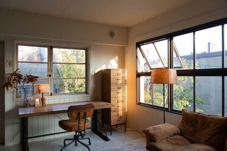 a simple desk made from wooden planks sits next to a wooden filing cabinet and a leather desk chair