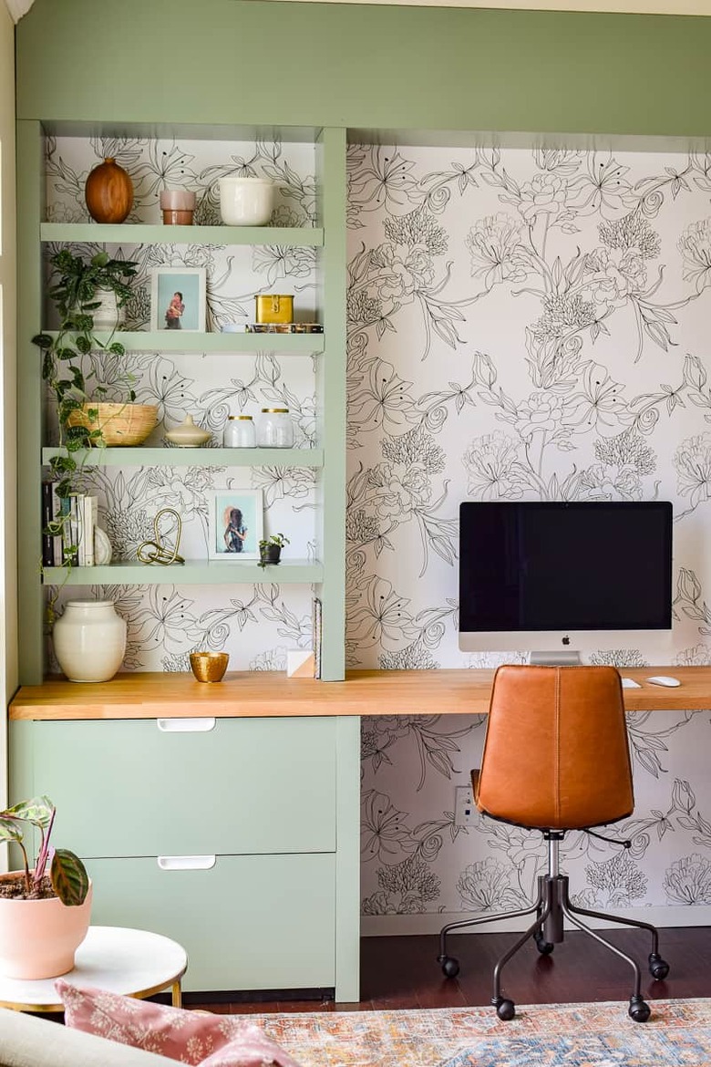 green home office built-ins with a black and white wallpapered backdrop, leather desk chair