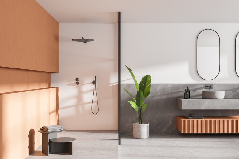 Interior of modern bathroom with white and wooden walls, concrete floor, double sink with two mirrors above it and shower cabin.