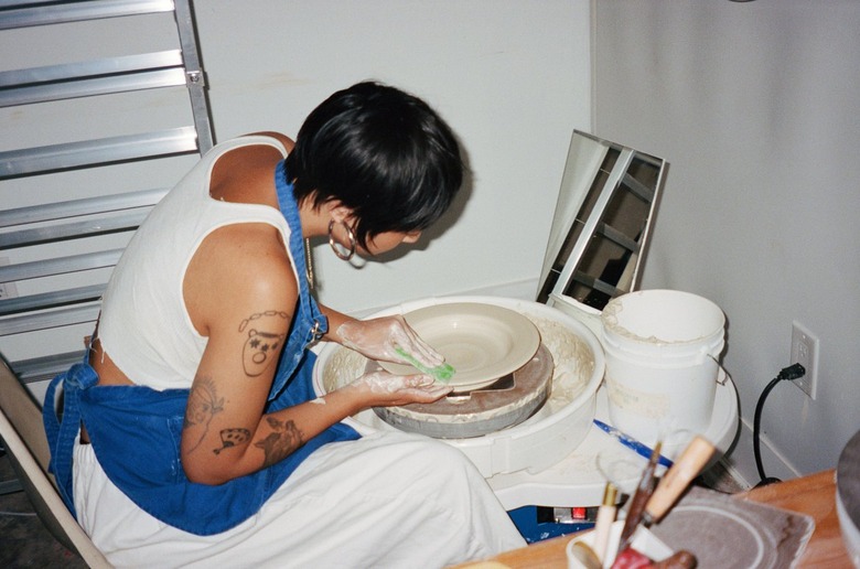 Victorio bent over a potter's wheel forming the clay into the shape of a bowl.