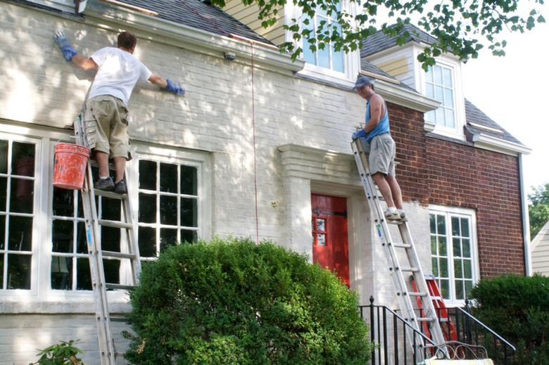 Men painting a brick house