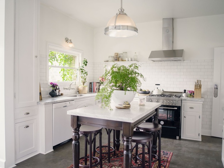 classic kitchen with white cabinets, white subway tile backsplash, marble countertops and espresso wood island with vintage rug