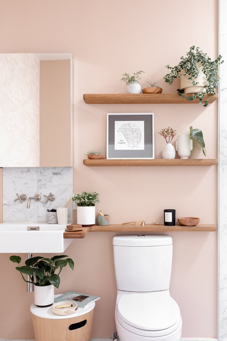 three wooden floating shelves above a toilet