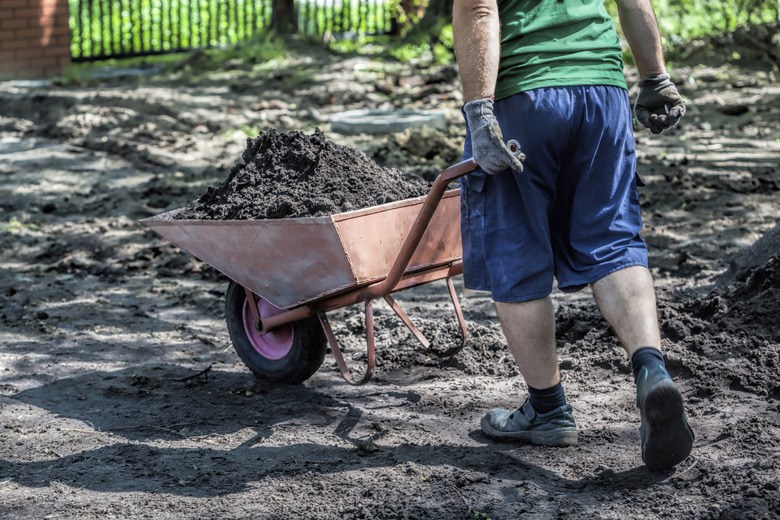 Man pushing wheelbarrow full of compost