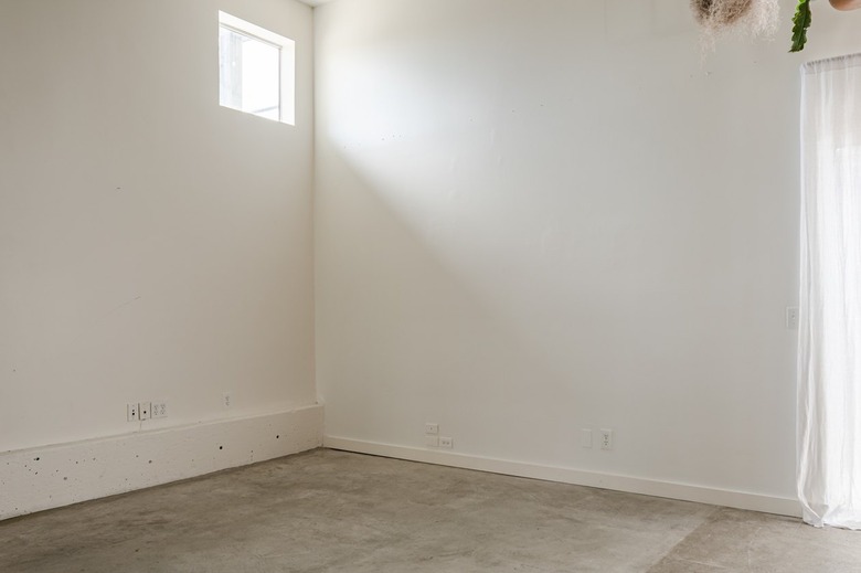 an empty white-walled room with a small, square window in the corner