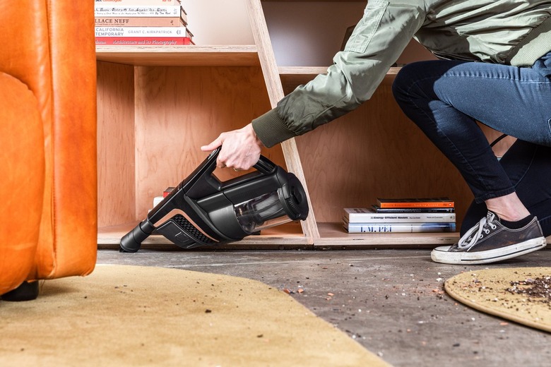 Handheld vacuum cleaning dirt on floor