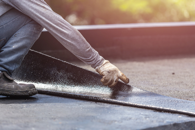 Group of worker installing tar foil on the rooftop of building. Waterproof system by gas and fire torching