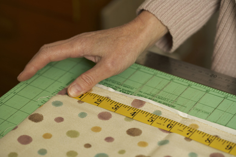 Close-up of hands of mature woman measuring textile