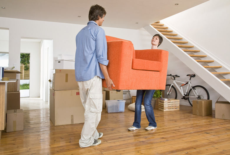 Couple carrying arm chair into new home