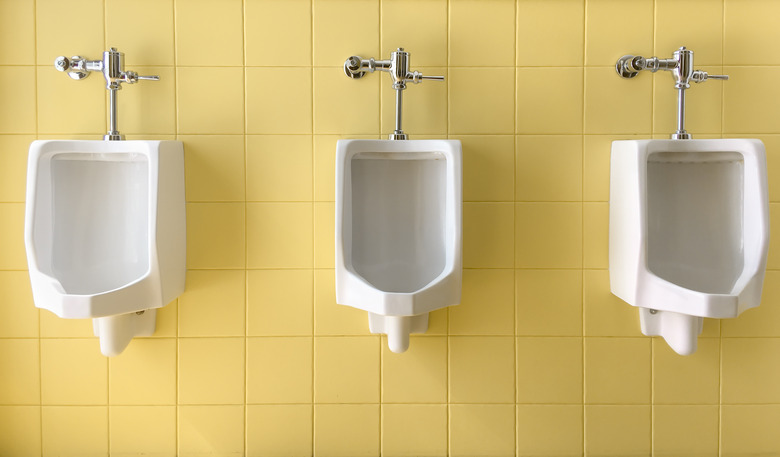 Close up row of outdoor white urinals men on yellow of wall public toilet.