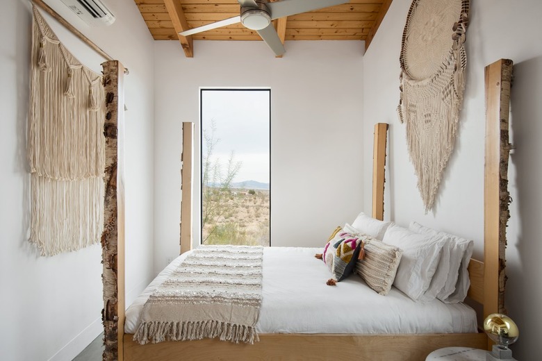 Minimalist bedroom with boho wall hangings and a rectangular window