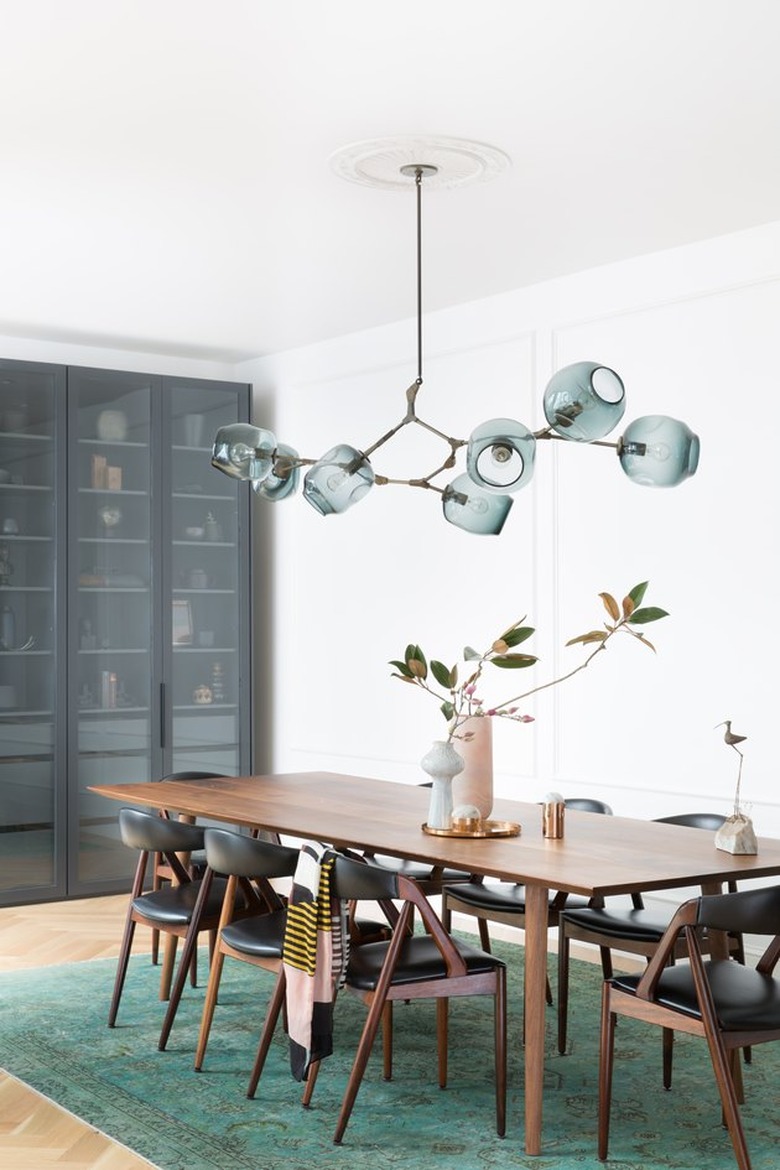 minimalist with color in white dining room with green rug and pendant light