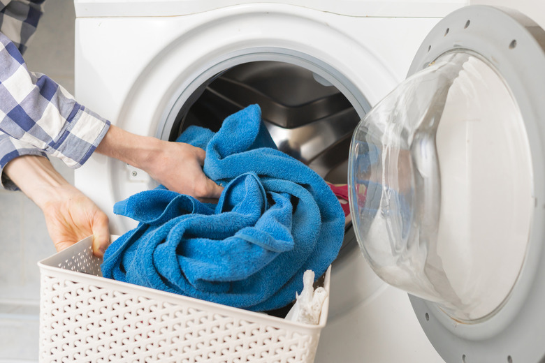 persons hand put dirty clothes in the washing machine b