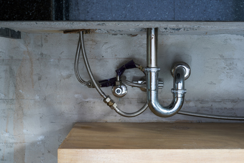 Bathroom steel sink pipes, trap and drain on concrete wall