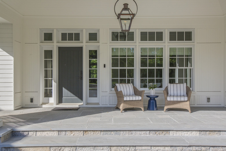 Gorgeous front porch with dark colored front door surrounded by windows