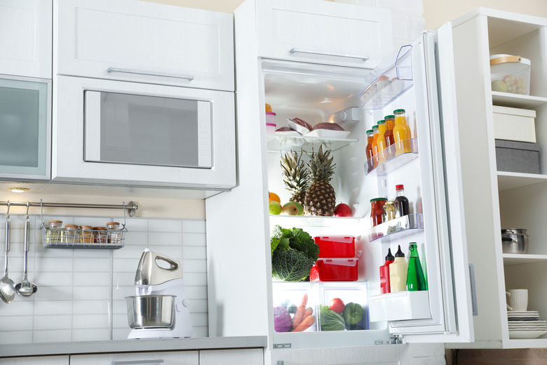 Open refrigerator full of products in stylish kitchen interior