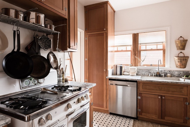 gas stove and cast-iron pans in a minimalist kitchen with black-and-white floor tiles