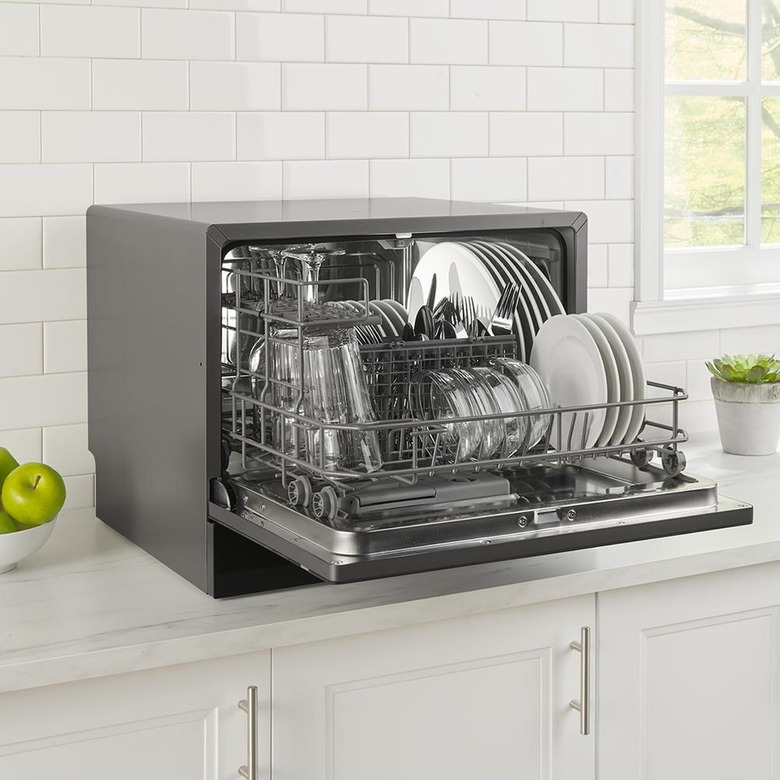 A stainless steel countertop dishwasher in a white kitchen