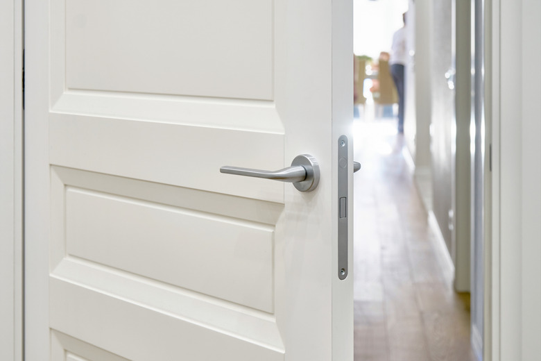 Open door with silver handle to room with oak parquet