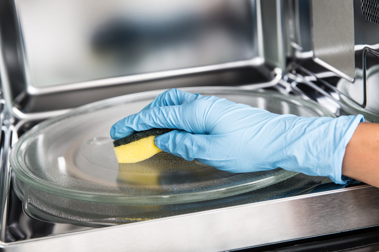 Woman hand cleaning microwave oven with sponge