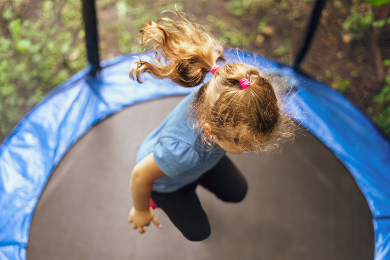 Kid jumping on a trampoline on a summer day.