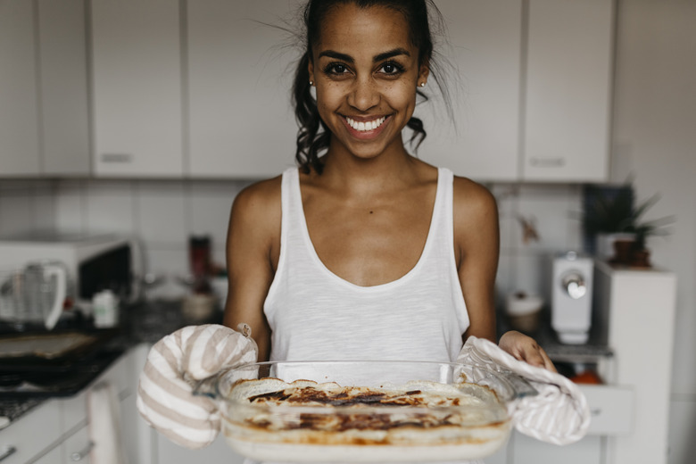 Portrait of smiling young woman with casserole in the kitchen