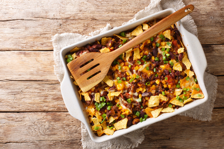 Crispy homemade frito pie with beef, cheese, corn, beans and chips close-up in a baking dish. Horizontal top view