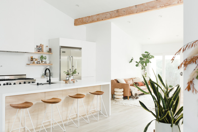 large airy kitchen with wood beam overhead and white waterfall countertop