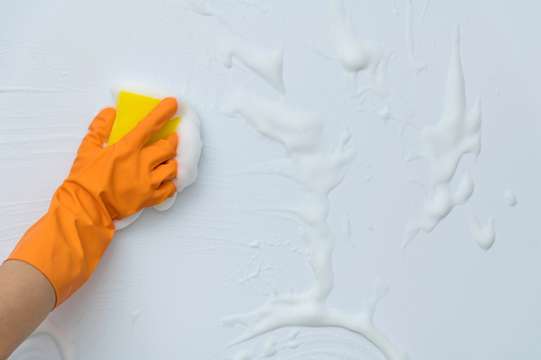 Cleaning blue wall with sponge.