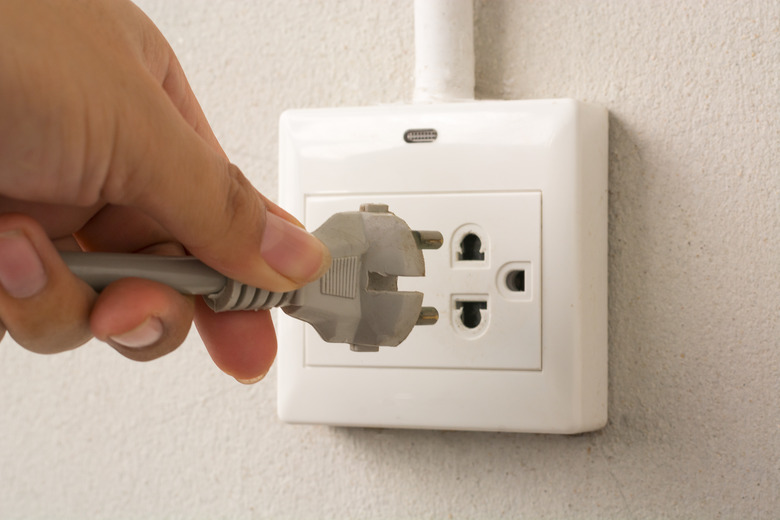 Male hand puts plug in the socket, closeup shot