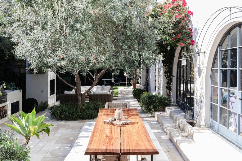 Wood patio table with plants and a white Mediterranean style building with arch windows